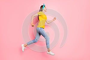 Full length profile side photo of charming youth running wearing yellow t-shirt isolated over pink background