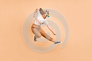 Full length profile side photo of young excited girl fight jump up ninja isolated over beige color background
