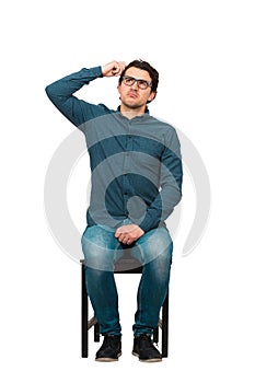 Full length of puzzled businessman, scratching head gesture, sitting on a chair isolated on white background. Business worker