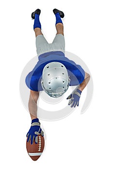 Full length rear view of American football player reaching towards ball