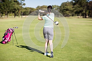 Full length rear view of golfer woman taking shot