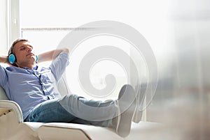 Full-length of relaxed Middle-aged man listening to music at home