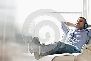 Full-length of relaxed Middle-aged man listening to music at home