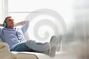 Full-length of relaxed Middle-aged man listening to music at home photo
