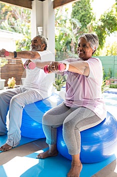 Full length of senior couple lifting dumbbells