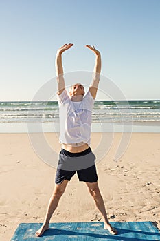 Full length of senior man practicing yoga at beach