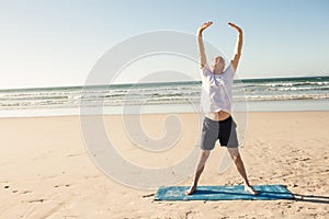 Full length of senior man stretching at beach