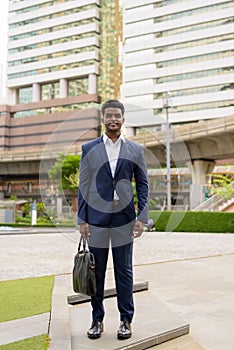 Full length shot of African businessman outdoors in city smiling