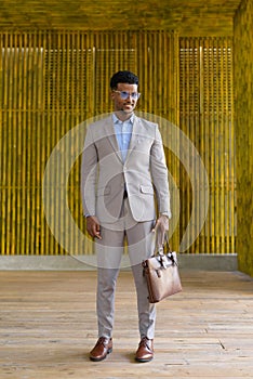 Full length shot of African businessman outdoors smiling and looking down