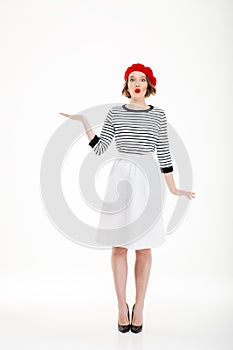 Full-length shot of amazed young woman looking camera and holding copy space on palm