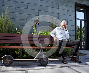 Full length shot of confident, cheerful middle aged businessman smiling while talking on the phone, sitting on the bench