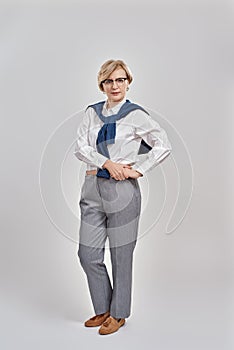 Full length shot of elegant middle aged caucasian woman wearing business attire and glasses looking at camera while