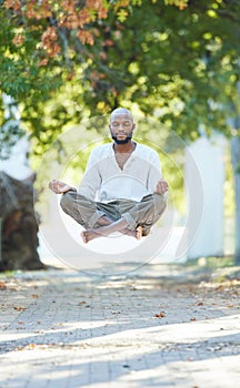 Yogas got him floating. Full length shot of a handsome young man levitating while meditating outside at the park.