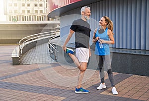 Full length shot of happy middle aged couple, man and woman in sportswear smiling, standing together outdoors ready for