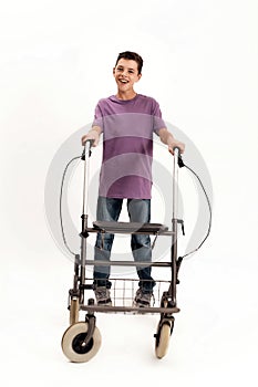Full length shot of happy teenaged disabled boy with cerebral palsy smiling at camera, taking steps with his walker