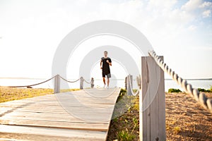 Full length shot of healthy young man running on the promenade. Male runner sprinting outdoors