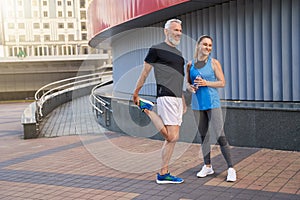 Full length shot of joyful middle aged couple, man and woman in sportswear smiling away, standing together outdoors