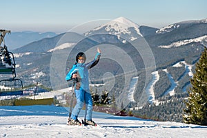 Full length shot of a smiling female skier showing thumbs up while skiing on the snowy slope at the winter ski resort