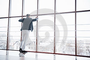 Full length shot of a stylish young businessman wearing a modern suit, who is a high achiever, standing on the top floor