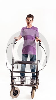 Full length shot of teenaged disabled boy with cerebral palsy in the glasses looking at camera, taking steps with his