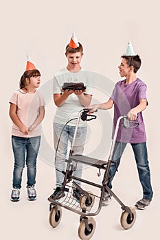 Full length shot of teenaged disabled boy holding cake while celebrating his birthday together with friends in birthday