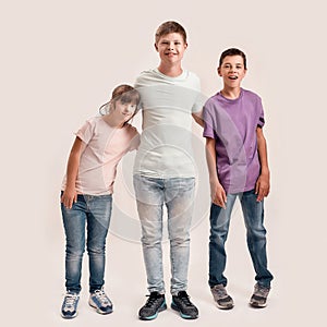 Full length shot of three cheerful teenaged disabled children with Down syndrome and cerebral palsy smiling while