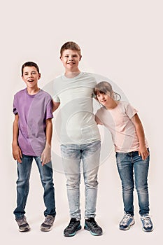 Full length shot of three cheerful teenaged disabled children with Down syndrome and cerebral palsy smiling while