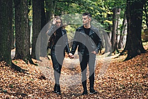 Full-length shot of young couple in love walking in the autumn park holding hands.