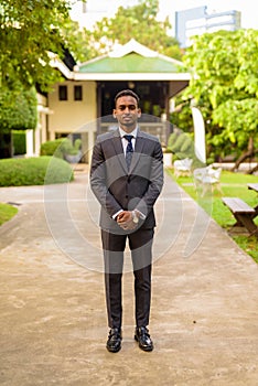 Full length shot of young handsome African businessman standing outdoors