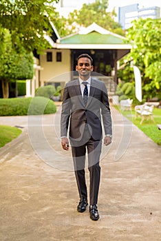 Full length shot of young handsome African businessman walking at park