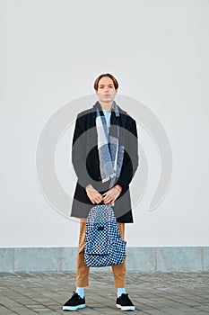 Full length shot of young student holds backpack in old wool coat, scarf and short trousers outdoor