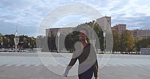 Full length side traveling young success Afro American business woman with suitcase going airport terminal, holding