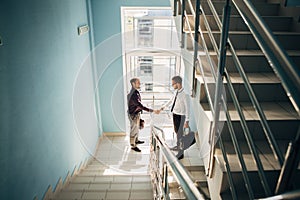 Full length side view of businessmen shaking hands in office building