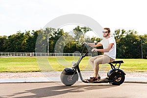 Full length side view image of cool man in sunglasses