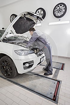 Full length side view of male automobile mechanic repairing car engine in repair shop