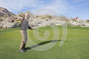 Full length side view of senior male golfer swinging his club at golf course