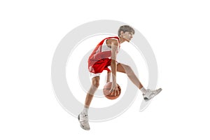 Full-length side view studio shot of young boy, basketball player in red uniform training isolated over white background