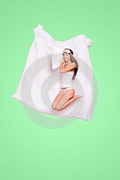 Full length size body young gorgeous smiling lady wearing eye mask, sleeping on pillow blanket and soft linen. Isolated