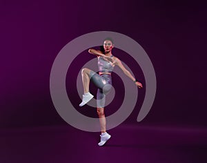 Full length of slim healthy woman warming up over a magenta background