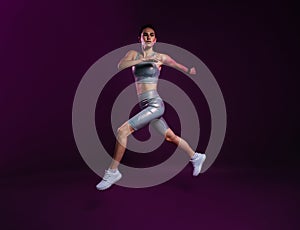 Full length of slim woman in silver sports clothes running