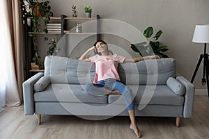 Full length smiling Arabian woman relaxing on couch at home
