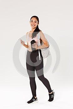 Full length of smiling healthy, slim asian girl going fitness training, female athelte carry backpack with workout