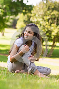 Full length of a smiling woman sitting on grass in park