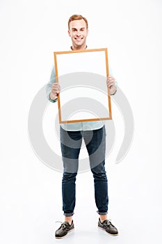 Full length of smiling young man holding blank whiteboard
