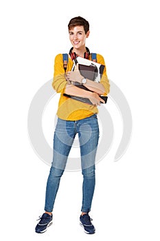 Full length smiling young woman with bag and books against isolated white background