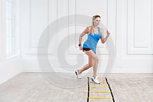 Full length of sporty beautiful young athletic blonde woman in black shorts and blue top are cardio workout with speed straps on photo