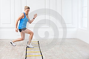 Full length of sporty beautiful young athletic blonde woman in black shorts and blue top are hard working and training on agility