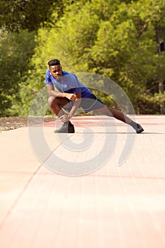Full length sporty black man doing exercise stretches outside