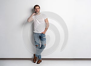 Full length studio portrait of casual young man in jeans and shirt. Isolated on white background.