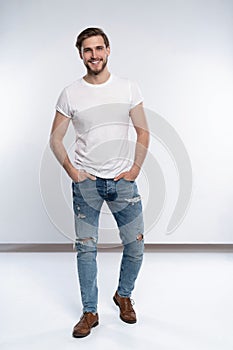 Full length studio portrait of casual young man in jeans and shirt. Isolated on white background.